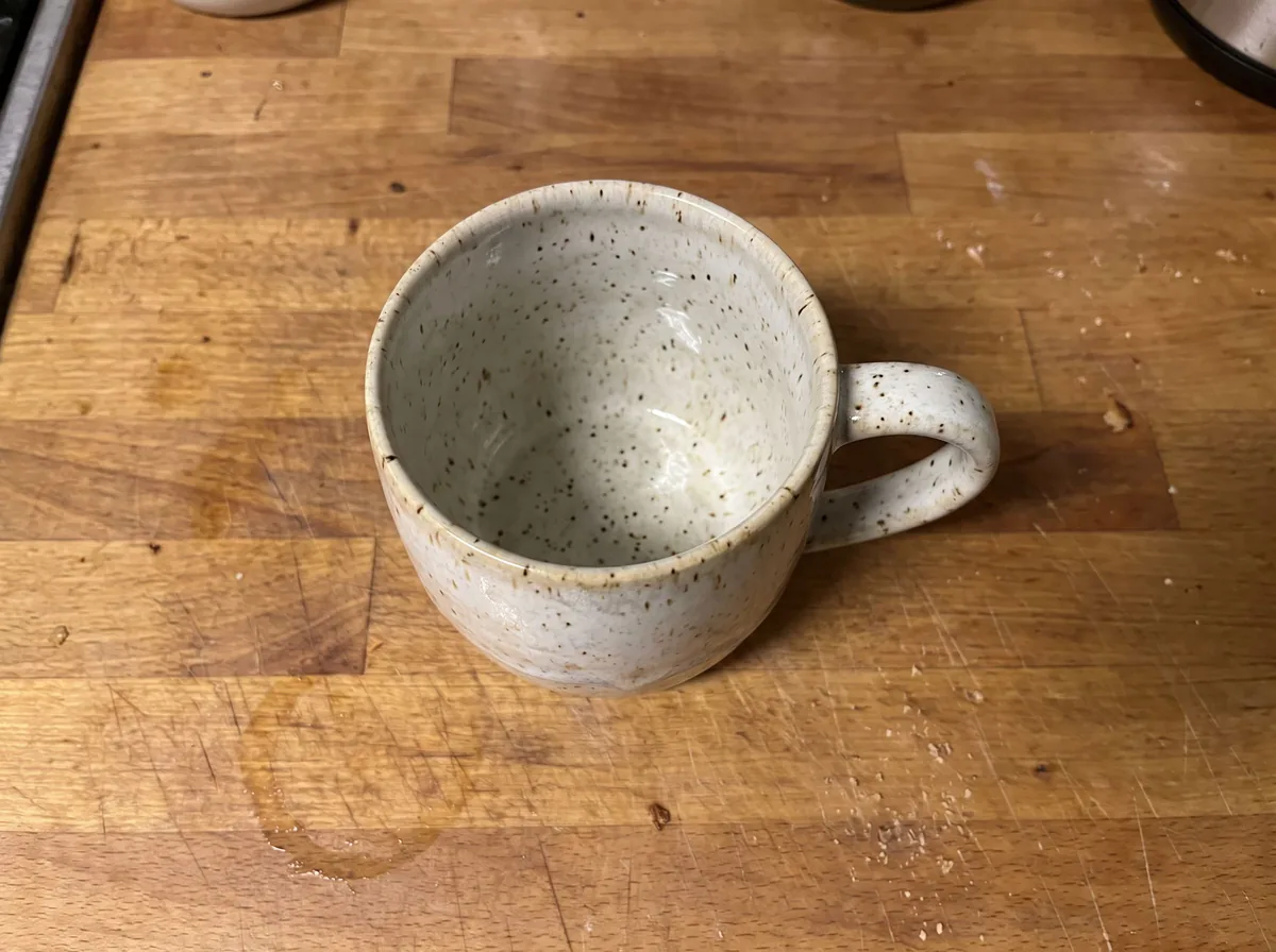 A plain phone photo of a stoneware mug on a kitchen counter